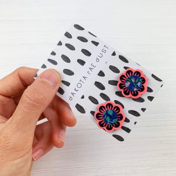 neon coral and navy floral stud earrings on a monochrome patterned backing card