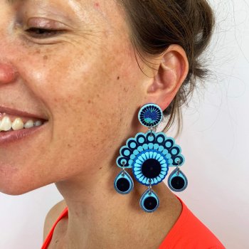 Chandelier style statement earrings worn by a smiling model