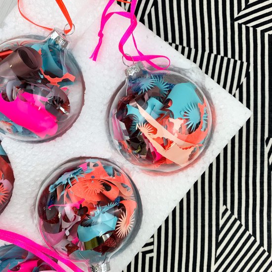 a set of five pink peach blue baubles against a black and white stripey background