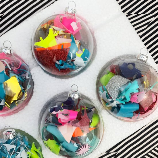 a tray of colourful Christmas baubles filled with fluorescent vinyl waste on a black and white striped backdrop
