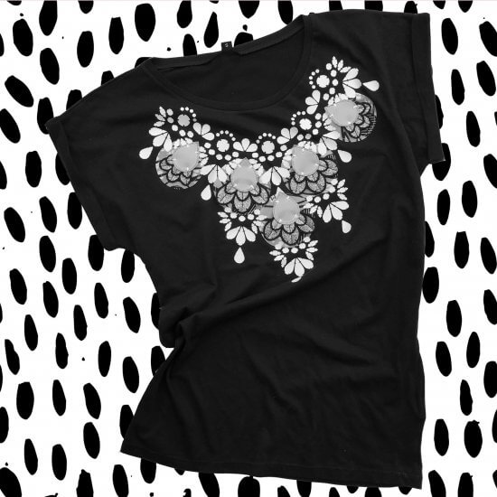 Slim fit T-shirt with an embellished neckline photographed against a black and white patterned background. This image is black and white