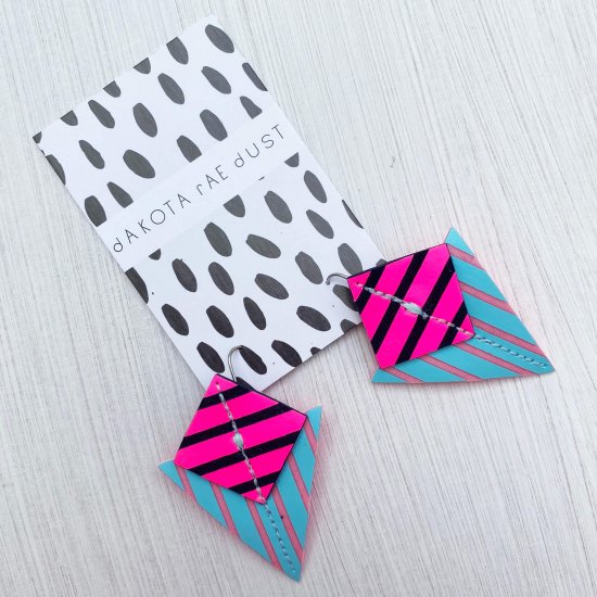 A pair of stripey triangle earrings in neon pink and blue