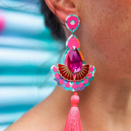 A close up of a woman's neck and ear focusing on her neon pink going out earrings. The earrings have fluorescent pink tassels.