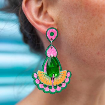 A close up of a woman's ear and neck, focusing on the emerald green jewel earrings she is wearing