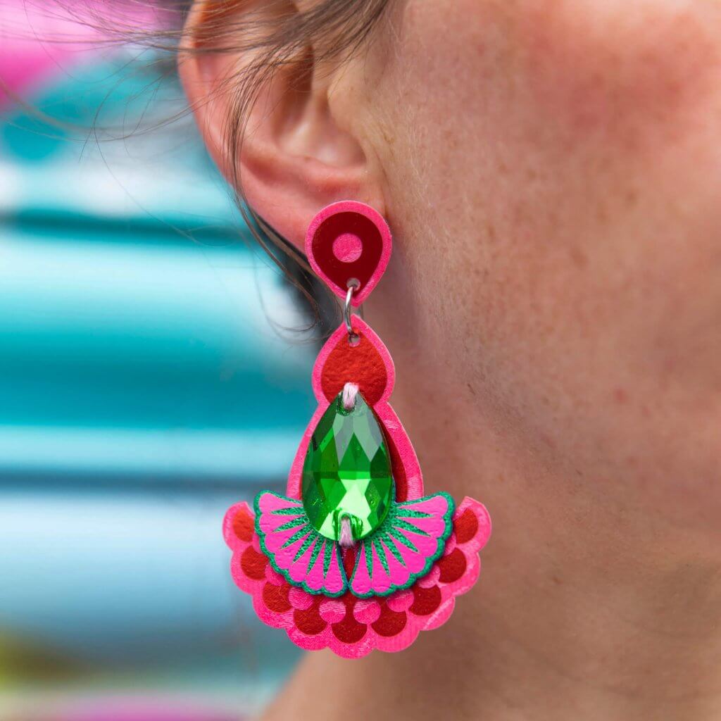 A close up of a woman's ear and neck, focusing on the laser cut statement earrings she is wearing