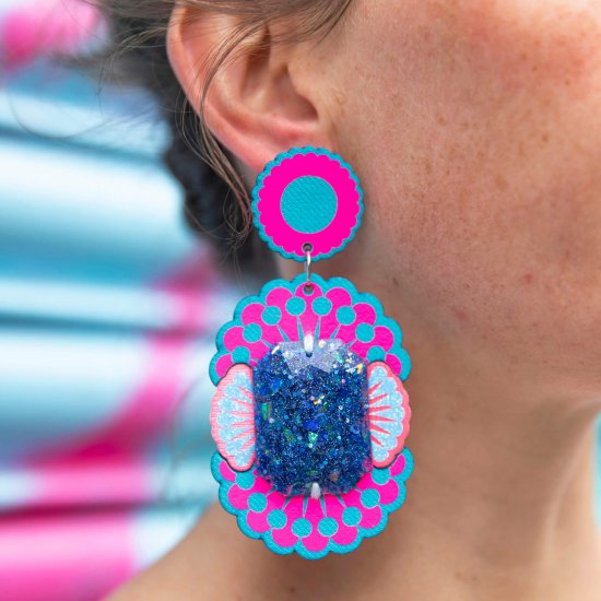 A close up of a woman's neck and ear, focusing on her colourful fluorescent pink and turquoise blue oversize jewel earrings.