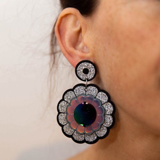 A close up of a woman's neck and ear focusing on her oversize flower motif earrings