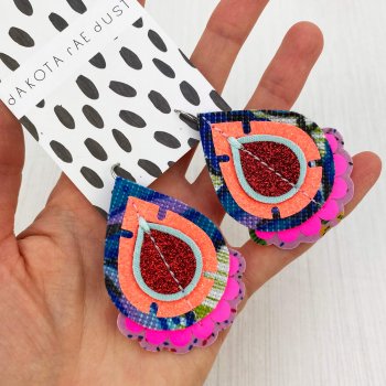 A pair of colourful vintage fabric earrings held in a open hand