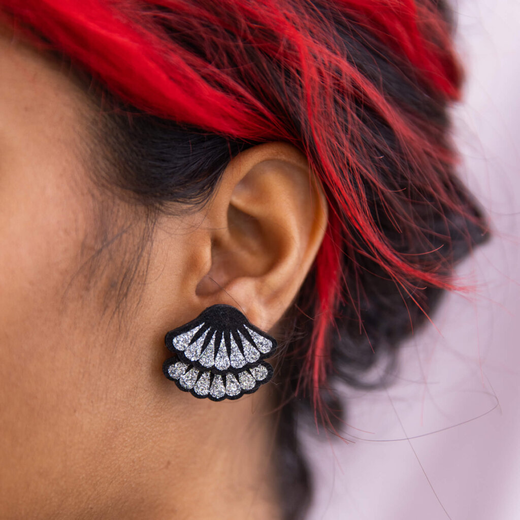 A close up of a woman's ear focusing on her silver glitter frill studs.