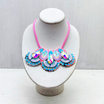 A pastel pink and blue mini bib necklace adorned with iridescent jewels is displayed on a white mannequin neck