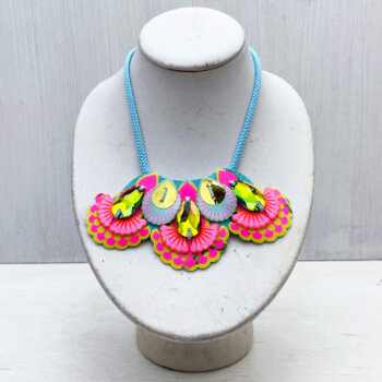 A mini jewel necklace in neon rainbow colours is displayed on a white mannequin neck in front of an off white background