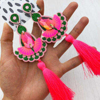A pair of luxury neon pink and green glitter tassel earrings with silky fluoro tassels are held in an open hand