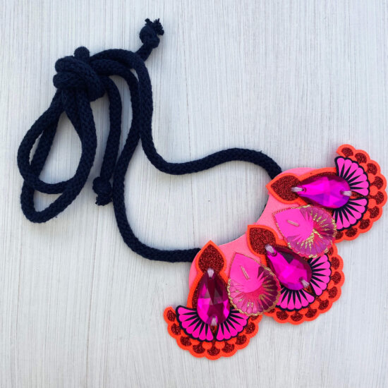 A navy, orange and hot pink mini bib necklace with navy cords is displayed on a white background