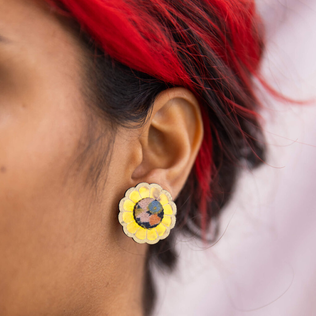 A close up of a woman's ear focusing on her gold festive flower studs.