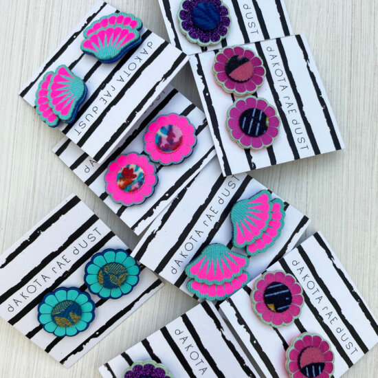 A selection of colourful studs mounted on black and white striped, dakota rae dust branded cards