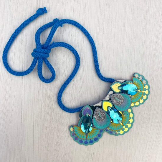 A blue yellow bib necklace with bright blue cords on an off white background